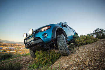Close up wide angle image of a modified 4x4 pick up truck driving on a 4x4 track in nature.