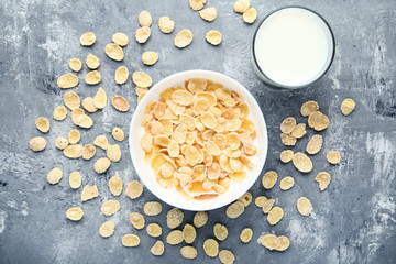 Corn flakes with glass of milk on grey wooden table