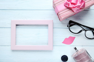 Obraz na płótnie Canvas Pink wooden frame with gift box, glasses and perfume bottle. Boss day concept