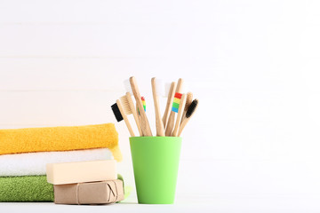 Bamboo toothbrushes with soap and folded towels on white background