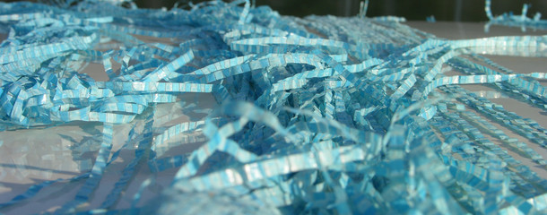 fragments of old blue polyethylene tarpaulin lie randomly on the metal surface.  the wind and the sun (element) fancy mixed stripes tarpaulin between them. close up.  shallow focus.