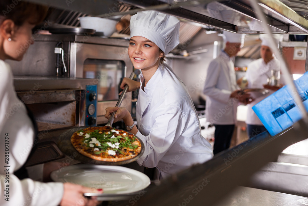 Wall mural female chef giving cooked pizza to waitress