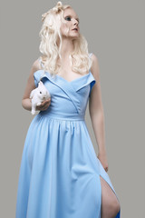 Albino blond girl in elegant dress posing with cute little rabbit