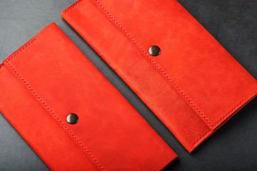 A pair of red genuine leather wallets with rivets on a dark background top view. Genuine leather