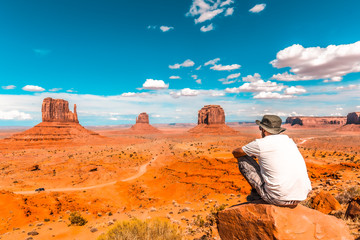 A young boy in a white T-shirt sitting to the right of the photo on a stone in the Monument Valley National Park in the visitor center. Utah