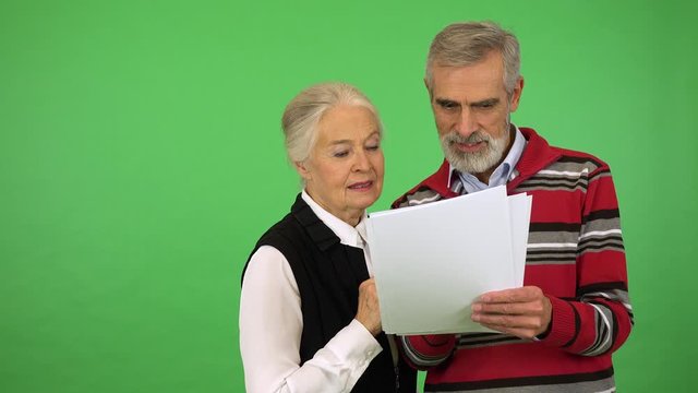A happy elderly couple reads a bunch of papers - green screen studio