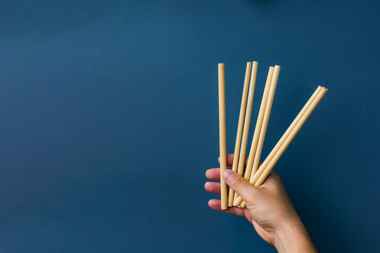 Bamboo Straws In A Hand In Blue Background