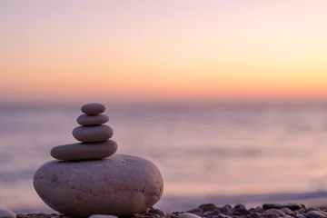 Foto op Canvas Perfecte balans van stapel kiezelstenen aan zee richting zonsondergang. Concept van evenwicht, harmonie en meditatie. Iemand helpen of ondersteunen om te groeien of hogerop te komen. © Juliaap