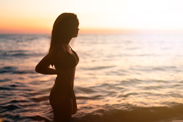 Silhouette of beautiful young gracile pensive woman with a freedom feeling at a beautiful sunset. Freedom and travel adventure happy feeling concept.