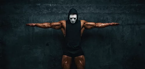 Wallpaper murals Carnival Mysterious Muscular man hiding behind mask Flexing Muscles. Bodybuilder with mask on his face posing.