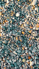 Abstract background of small pebbles. Pebble texture with a blue tint. Stone background. Pebble beach with multi-colored stones. Turquoise. Vertical frame