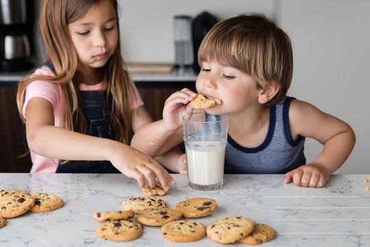 Siblings eating cookies and milk