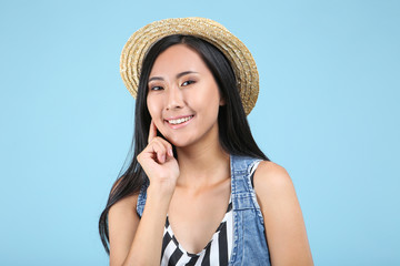 Beautiful young woman in straw hat on blue background