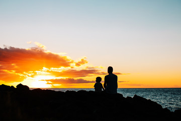 Silhouette of man and boy on the beach with incredible ocean sunset in island Maui, Hawaii