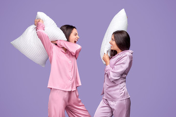 Young women having pillow fight during sleepover