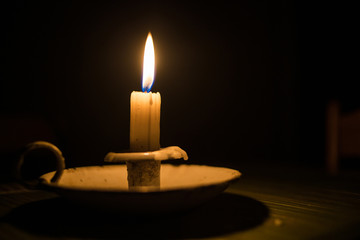 Close up image of a candle burning in a dark room