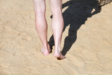 Man legs on sand. Male feet walking on beautiful sandy beach of hotel resort on Red sea in Egypt, doing and leave behind footprints in sand. Man on vacation in summertime. Travel and holiday concept.