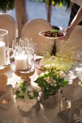 Outdoor wedding celebration at a restaurant. Festive table setting, catering. Wedding in rustic style in summer, beautiful small bouquets on a table.