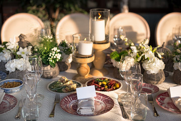 Outdoor wedding celebration at a restaurant. Festive table setting, catering. Wedding in rustic style in summer, beautiful small bouquets on a table.