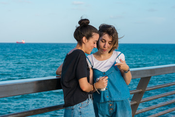 Two young women looking an instant photo in the coast