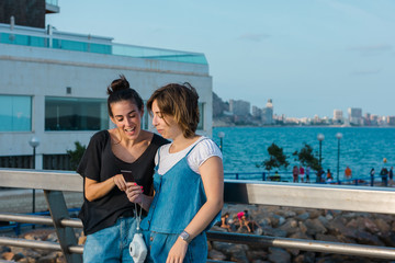 Two young women looking an instant photo in the coast