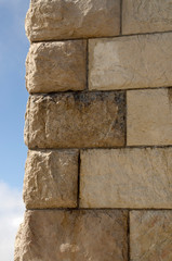 Corner of a brick high wall against a blue sky.