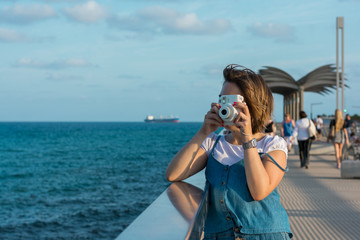 Young woman with a instant camera in the coast
