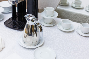 Metal teapot and a set of cups for tea serving. Catering food, buffet with tea