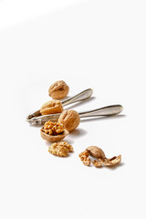 group of cracked walnuts and a nut cracker on a white backdrop in a soft backlight