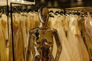 Metal mannequin imitating female figure, white wedding dresses on background