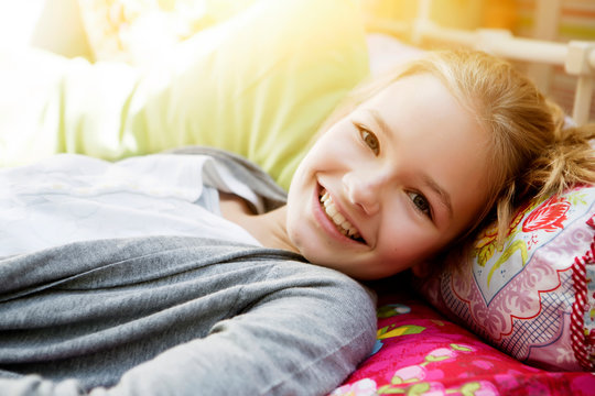 Smiling girl lying on bed, portrait