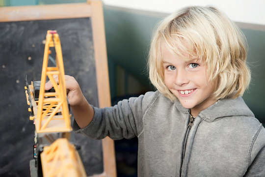 Blond boy playing with toy crane