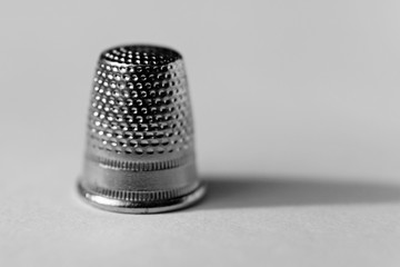 a thimble in close-up on white background, the whole picture in black and white, lighted in daylight on the Umedalen