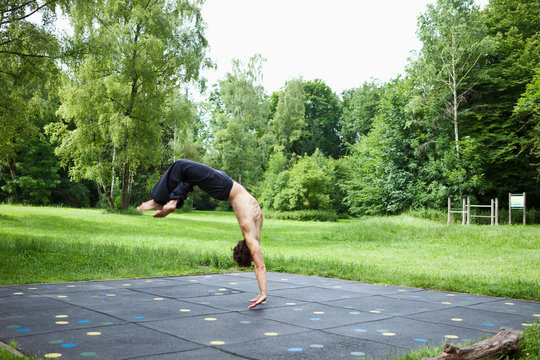 Germany, Bavaria, young man performing somersault