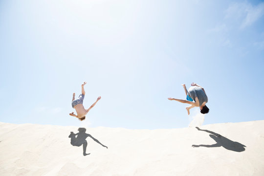 France, Two Boys jumping on sand dune
