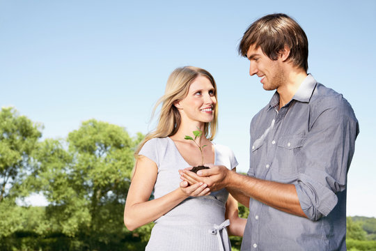 Germany, Cologne, Young couple holding seedling