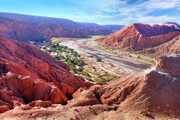 Desert landscape of village and dry river near San Pedro de Atacama, Chile, viewed from Pukara de Quitor, against a blue sky covered by clouds.