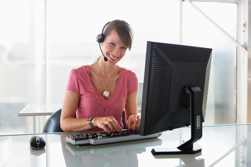 Woman working on computer, wearing headset