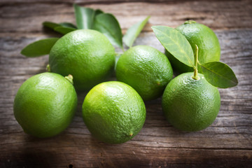 Fresh limes on old wooden background. With dark vignette. Favorite vegetable for sour taste.