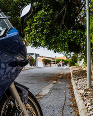 motorcycle in abandoned street of mijas costa with leafy trees and building in the background