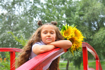 Portrait of a beautiful young Schoolgirl on the background park and red bridge