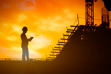 Silhouette of inspector working at construcktion on twilight background.