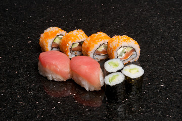 Sushi rolls on black marble background. Fresh Hosomak, Maki, Nigiri, Tempura, Uramaki, Philadelphia pieces with rice, nori and fish. Japanese cusine, Asian food.