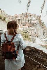 Woman in casual dress with backpack looking to sea. Travel Cingue Terre in Italy in summer
