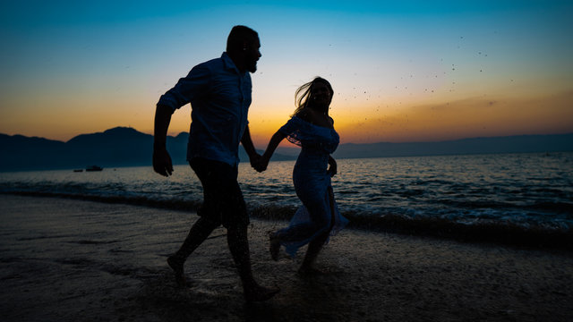 silhueta casal, casal correndo na praia, namorados, amigos no por do sol