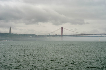 25th of April Suspension Bridge over the Tagus river in Lisbon, Portugal Havy rainy clouds and fog at Ponte 25 de Abril, Lisboa, Portugal