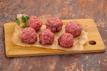 Raw meatball over wooden background