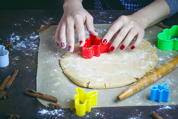 Female hands in flour making Christmas cookie in the form of gingerbread man from dough in kitchen. Home baking process