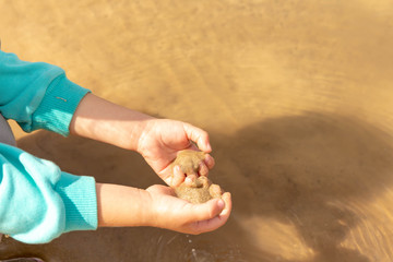 Children's pens hold wet sand above the water surface.
