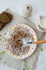 Traditional Russian food. Buckwheat porridge with milk and black bread on the table. Horizontal orientation.